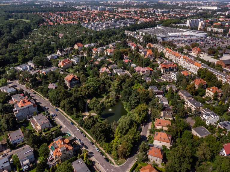 Skwer przy Anielewicza - ujęcie z lotu ptaka na staw, widoczne okalające go zadrzewienie i zabudowa miasta. lotu ptaka na staw, widoczne okalające go zadrzewienie i zabudowa miasta.