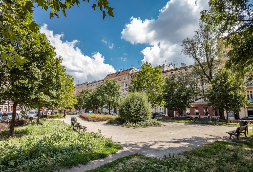 Skwer przy ul. Św. Wincentego- widok na prostokątny plac, w centrum grupa krzewów.