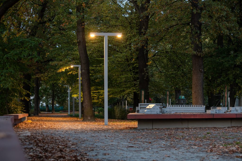 Skwer przy ul. Zielonego Dębu- zdjęcie wykonane o zmroku. Widoczna oświetlona przez lampy ścieżka oraz fragment makiety osiedla.