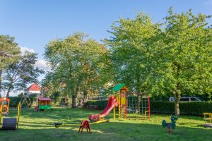 Zieleniec przy ul. Osinieckiej- ujęcie na plac zabaw, widoczny domek ze wspinaczką, huśtawka i bujak na sprężynie.