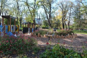 Park Aleksandry Natalli-Świat- widok na ogrodzone rabaty i sprzęty do zabaw.