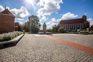 Bulwar ks. Aleksandra Zienkiewicza - widok na granitowy Pomnik Papieża Jana XXIII, po lewej stronie nasadzenia bylin, po prawej stronie kościół.