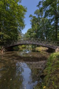 Park Szczytnicki- widok na rzekę i stalowy most, po obu stronach towarzyszące zadrzewienie.